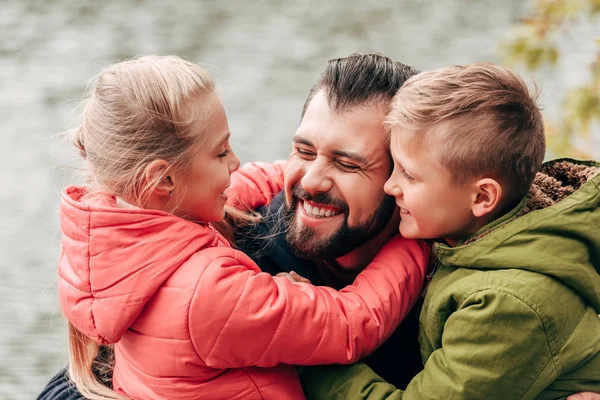 Счастливый отец и дети обнимаются в парке — стоковое фото