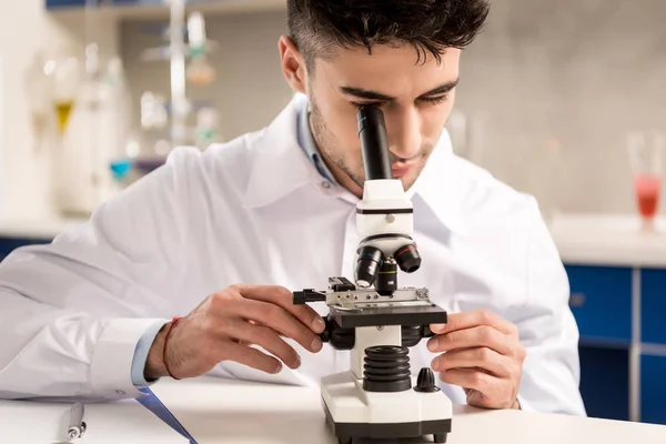 Químico trabajando con microscopio - foto de stock