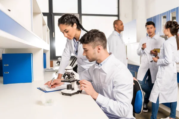 Técnicos de laboratório que trabalham com microscópio — Fotografia de Stock