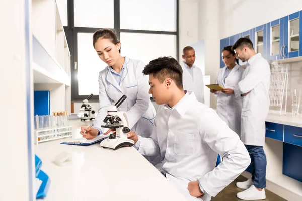 Techniciens travaillant au microscope — Photo de stock