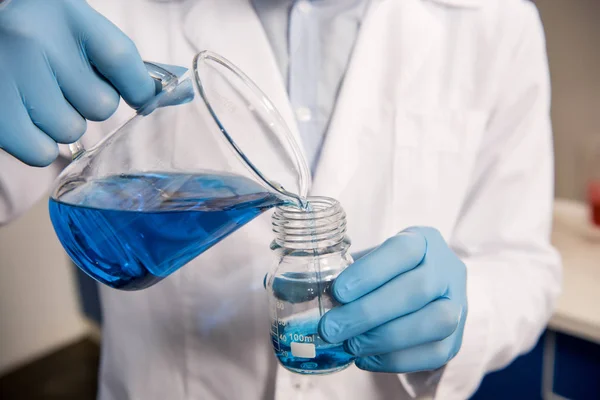 Scientist pouring reagent into jar — Stock Photo