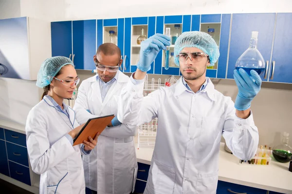 Cientista que examina tubos de ensaio em laboratório — Fotografia de Stock