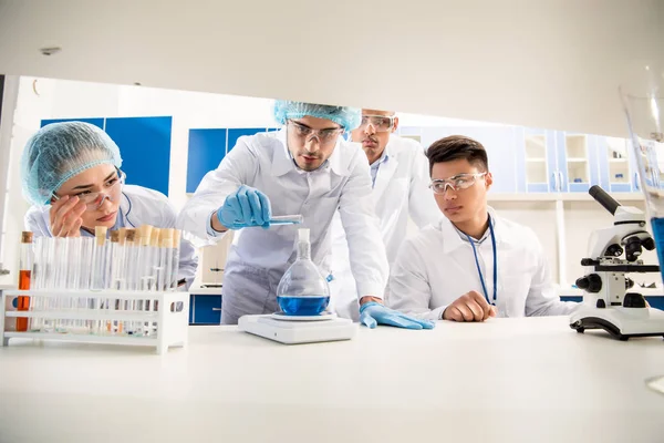 Scientists weighing flask with reagent — Stock Photo