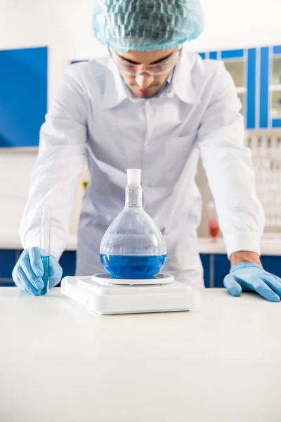 Pharmacy worker weighing flask — Stock Photo