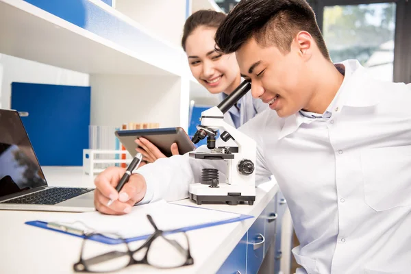 Científicos que trabajan con microscopio - foto de stock