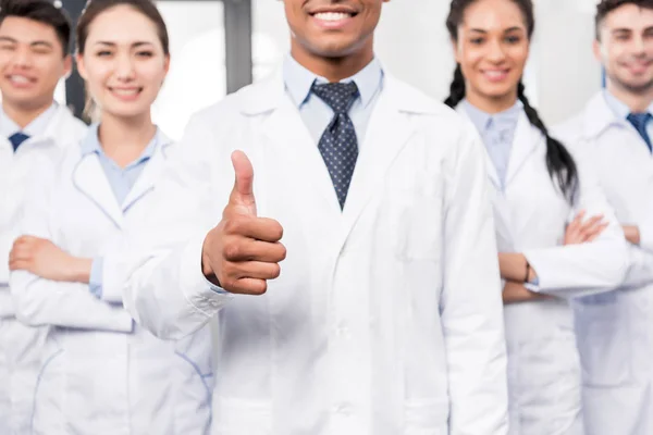 Doctor with team showing thumb up — Stock Photo