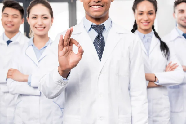 Doctor with team showing ok sign — Stock Photo