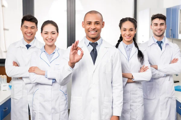 Arzt mit Team zeigt Okay-Zeichen — Stockfoto