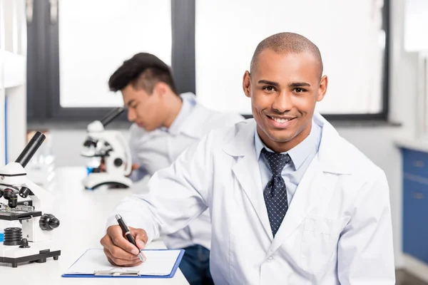 Doctor escribiendo notas en portapapeles - foto de stock