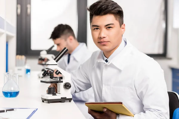 Jeune scientifique au microscope — Photo de stock