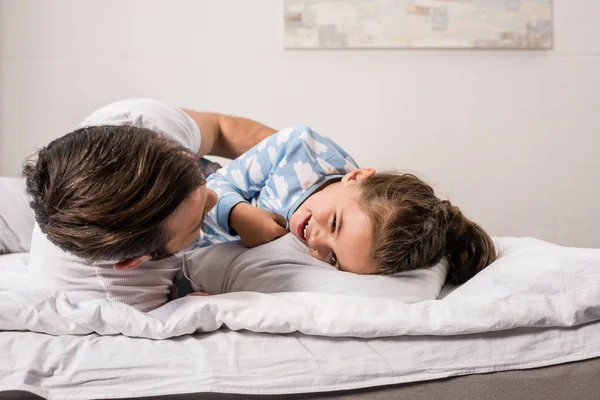 Padre e hija abrazándose en la cama - foto de stock