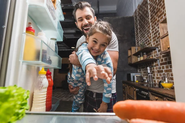 Padre con hija tratando de llegar a la comida - foto de stock