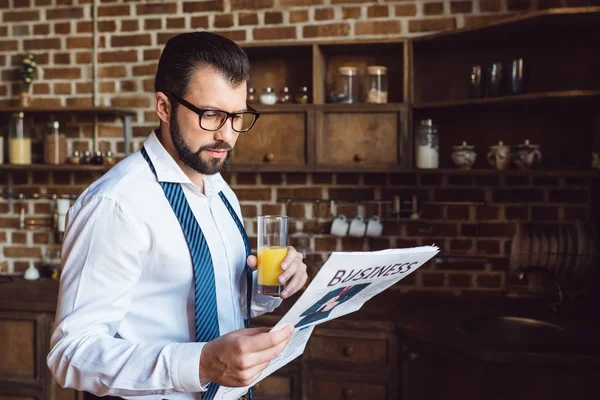 Businessman reading newspaper and drinking juice — Stock Photo
