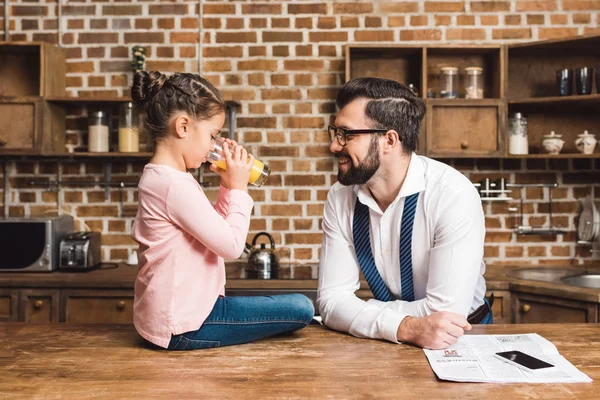 Father looking at daughter drinking juice — Stock Photo