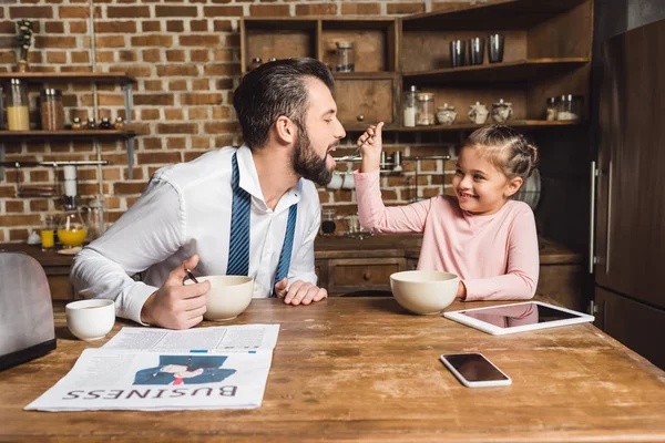 Daughter feeding father with cereal at morning — Stock Photo