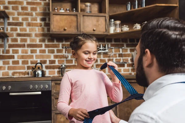 Daughter playing with fathers necktie — Stock Photo