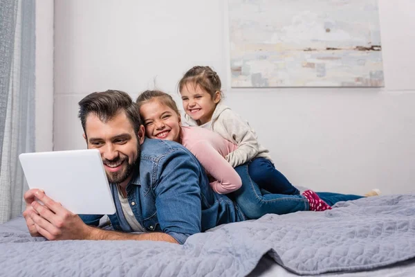 Padre e hijas relajándose en la cama - foto de stock