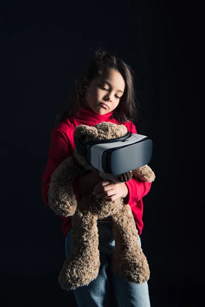 Ребенок надевает наушники на плюшевого медведя — стоковое фото