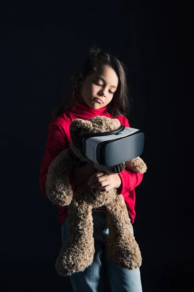 Niño poniendo auriculares VR en osito de peluche - foto de stock