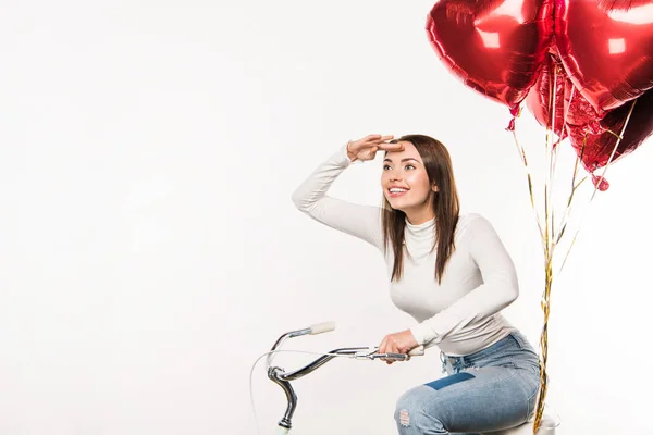 Woman sitting on bike with balloons — Stock Photo