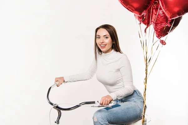 Woman sitting on bike with balloons — Stock Photo