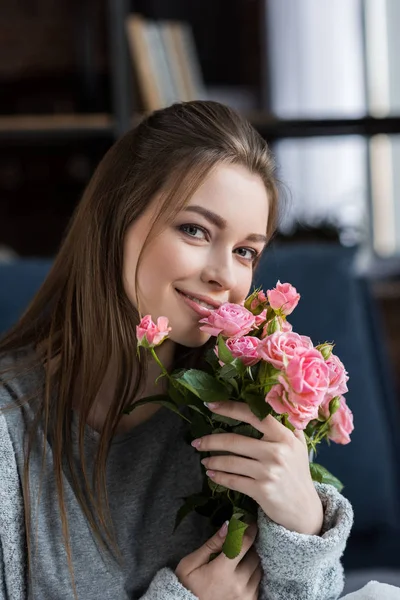 Happy girl hugging bouquet of pink roses and looking at camera, 8 march concept — Stock Photo