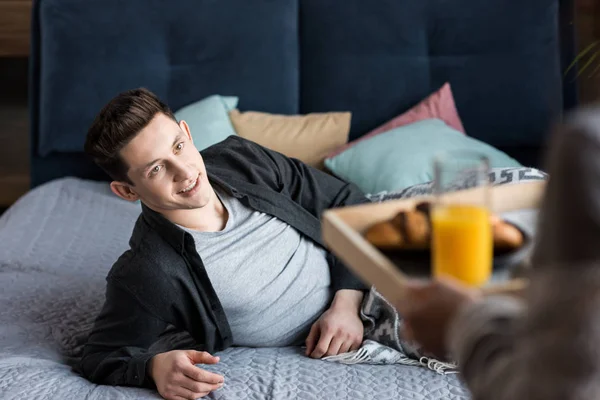 Cropped image of girlfriend carrying tray with breakfast to boyfriend — Stock Photo