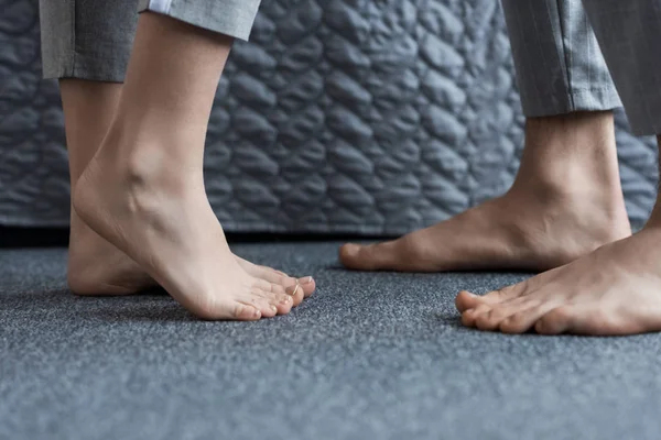 Cropped image of boyfriend and girlfriend standing barefoot on floor — Stock Photo