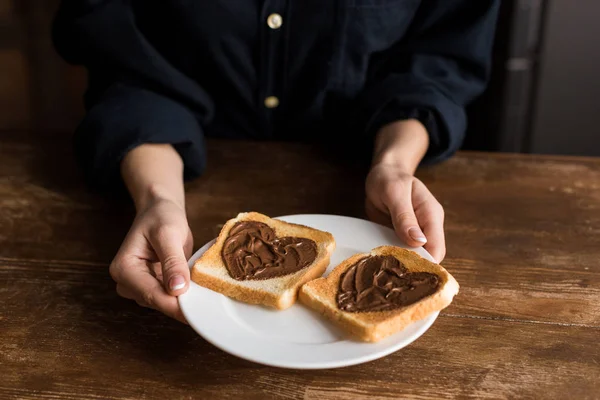 Imagem cortada de menina segurando prato com brindes com corações, conceito dia dos namorados — Fotografia de Stock