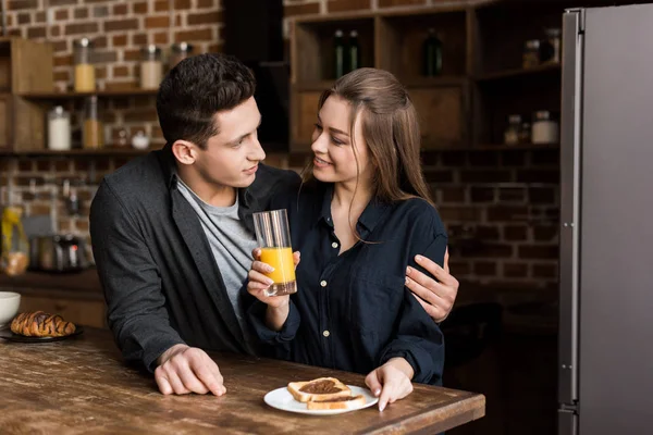 Namorado abraçando namorada com suco de laranja — Fotografia de Stock