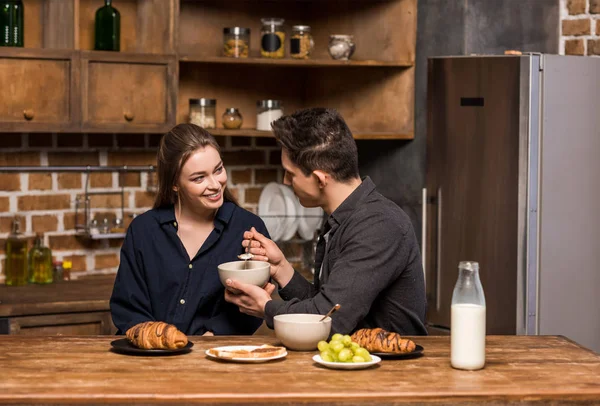 Novio pidiendo novia para degustar el desayuno en la cocina - foto de stock