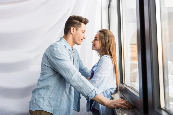Happy couple looking at each other near window — Stock Photo