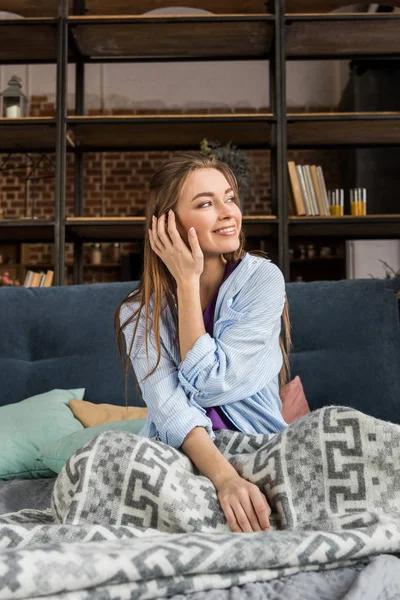 Heureuse fille assise dans le lit le matin et regardant loin — Photo de stock