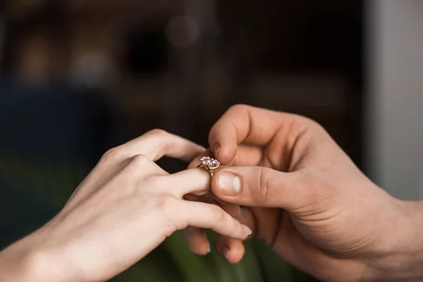 Cropped image of boyfriend proposing girlfriend and wearing engagement ring — Stock Photo