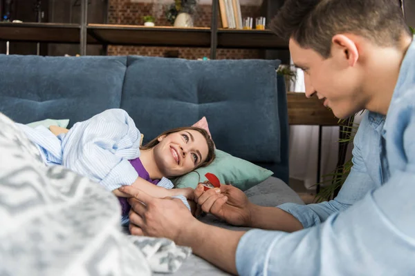 Freund macht Freundin Heiratsantrag und hält Verlobungsring in roter Schachtel — Stockfoto