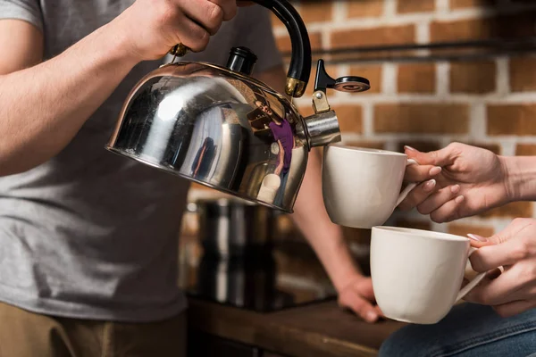 Imagen recortada de novio vertiendo café en tazas - foto de stock