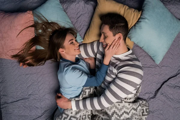 Vue de dessus de couple heureux étreignant et couché dans le lit — Photo de stock