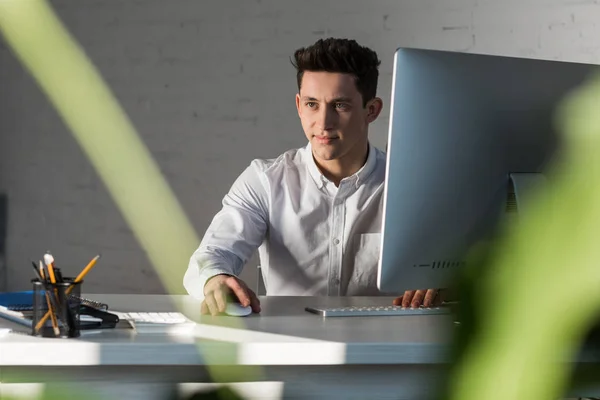 Усміхнений вдумливий бізнесмен сидить на робочому місці в сучасному офісі — стокове фото