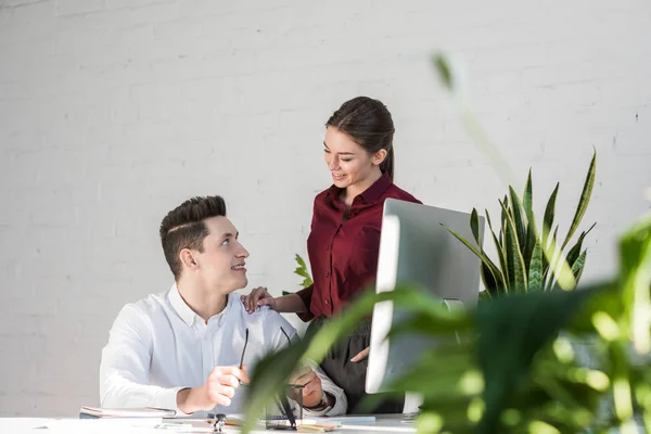 Jóvenes gerentes coqueteando en el lugar de trabajo en la oficina moderna - foto de stock