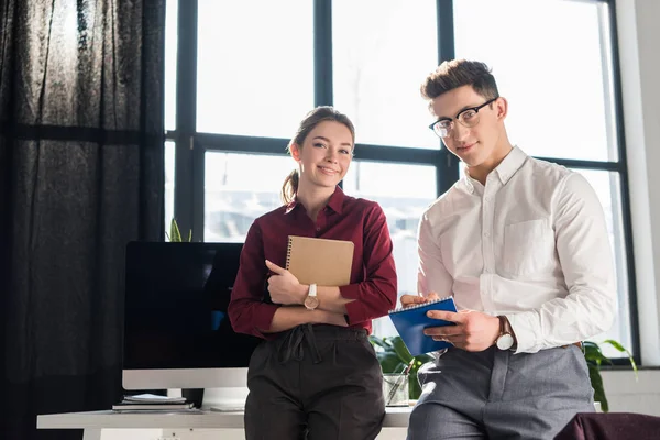 Partenaires commerciaux penchés sur le bureau et regardant la caméra — Photo de stock