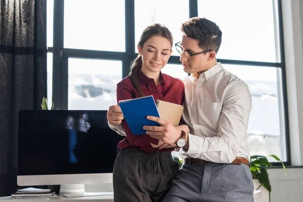 Feliz joven managers pareja abrazando en oficina, lugar de trabajo romance concepto - foto de stock