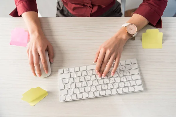 Recortado disparo de la gerencia escribiendo en el teclado con pegatinas en blanco en el escritorio de trabajo - foto de stock