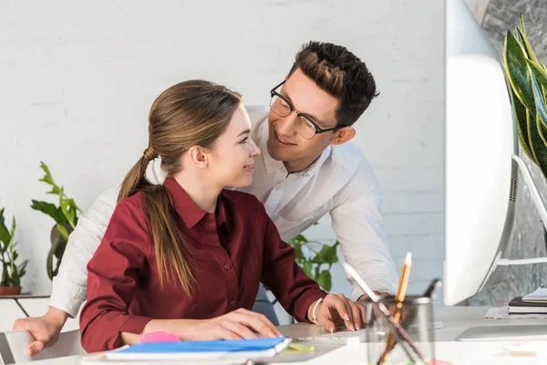 Jeune homme d'affaires séduisant flirtant avec une collègue féminine sur le lieu de travail dans un bureau moderne — Photo de stock