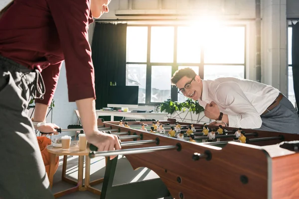 Parceiros de negócios felizes jogando futebol de mesa no escritório moderno — Fotografia de Stock