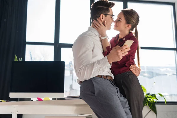Attrayant baiser jeune couple en vêtements formels au bureau — Photo de stock