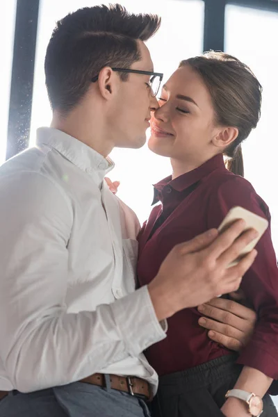 Attractive kissing young couple in formal clothing — Stock Photo