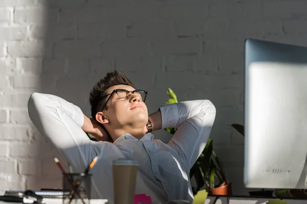Schöner junger Geschäftsmann entspannt sich am Arbeitsplatz im modernen Büro — Stockfoto