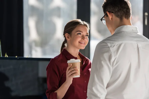 Attractive young manageress with coffee to go flirting with colleague — Stock Photo