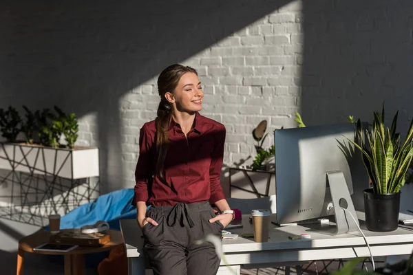 Hermosa joven empresaria apoyada en su lugar de trabajo en la oficina moderna - foto de stock