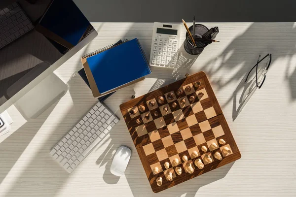 Top view of chess board at workplace with computer — Stock Photo